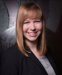 In a business portrait with a dark background, a young woman smiles directly at the camera