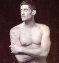 Black and white photo of a man unclothed from the waist up, crossing his arms over his stomach and, with eyes closed, turns his gaze off camera.