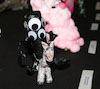 Close up of handmade little figures arranged on a table. Focus is on a black stick with googly eyes on a tiny horse and puffy pink guy.