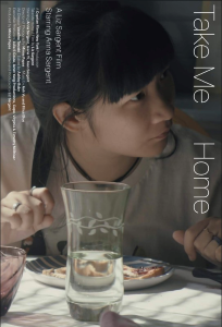 Movie poster. Close up of a young woman seated in front of a plate of food and glass of water. She looks to one side with a concerned expression and hovers both hands above her table setting. The text Take Me Home appears in white text running down one side of the image, while smaller text with film credits is on the other side.