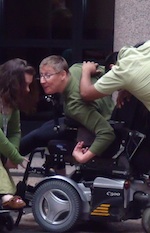 Susie curls around the arm of her power chair in a trio of dancers.