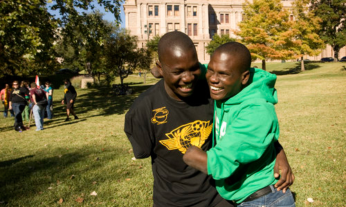 two men with above- and below-the-elbow amputations embrace and smile broadly